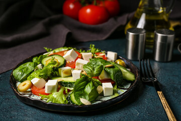 Plate of healthy vegetable salad with napkin and cutlery on blue grunge table