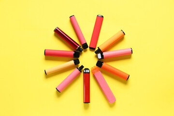 Frame made of different electronic cigarettes on yellow background