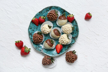 Plate with chocolate covered strawberries and fresh berries on white background
