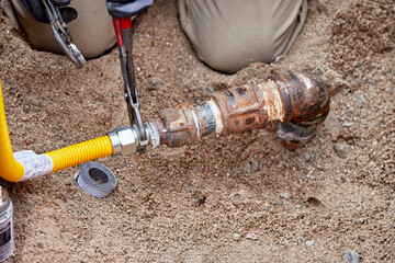 A Plumber hooking up a temporary gas line to a propane tank