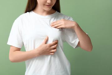 Young woman checking her breast on green background