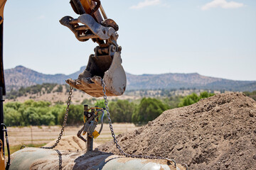 Preparing to lift out a buried propane tank with the bucket on an excavator