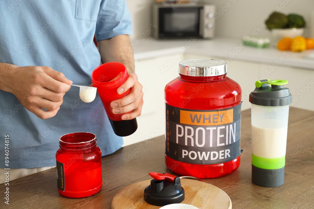 Canvas Prints Sporty young man with protein powder in kitchen, closeup