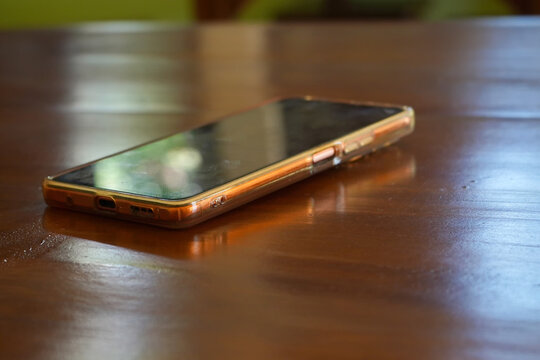 A shiny gold smartphone rests on a wooden table.