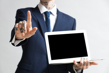 Young businessman with laptop using virtual screen on grey background, closeup
