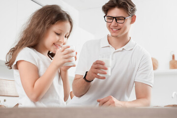 Little girl with her father drinking milk in kitchen
