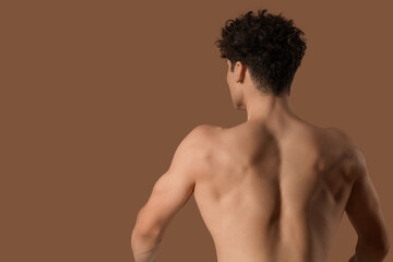 Fototapeta premium Muscular young man on brown background, back view