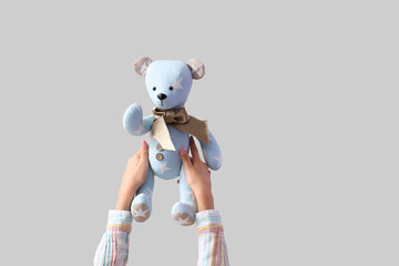 Child with toy bear on light background