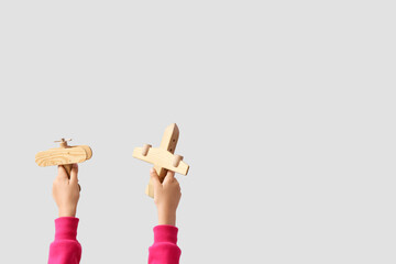 Child with wooden planes on light background