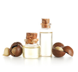 Bottles of macadamia oil and nuts on white background