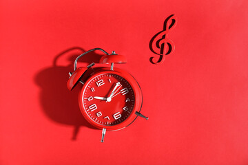 Vintage alarm clock and violin clef on red background