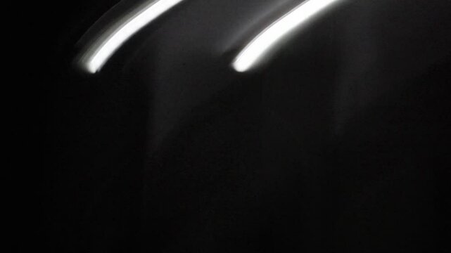 Primer plano de una luz de una lampara con un bombillo de color blanco en movimiento de forma circular en la oscuridad. C&aacute;mara en movimiento.