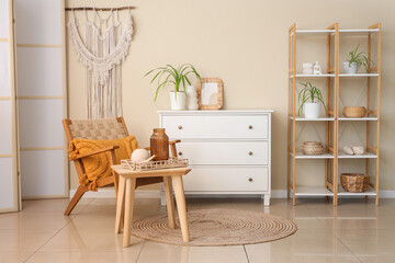 Interior of living room with armchair, drawers and shelf unit