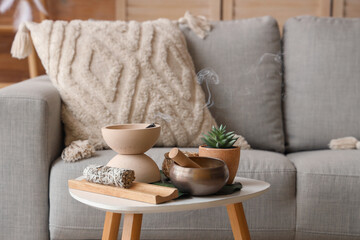Tibetan singing bowl with Palo Santo and plant on table in living room, closeup