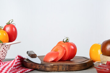 Wooden board with cut fresh tomato on grey table