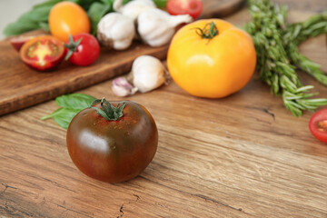 Different fresh tomatoes with garlic and rosemary on wooden background