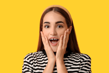 Surprised young woman with diastema on yellow background, closeup