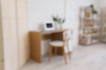Blurred view of living room with workplace and shelf unit