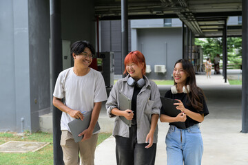 Group of Happy Students Walking on Campus with Laptops and Headphones, Smiling and Enjoying University Life