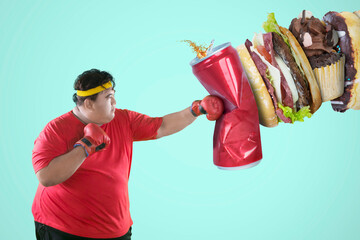 Picture of an Asian obese man wearing sportswear while punching unhealthy foods in green screen...