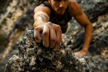 Close-up of a climber's hand gripping a rock, intense focus and effort in a rugged mountain environment