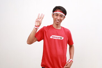 Asian young boy with red white ribbon for celebrating Indonesia independence day standing while showing three fingers