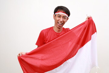 Asian men standing to celebrate Indonesia's independence raised red and white flags while shouting...