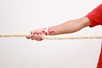 close up photo of Asian men celebrating Indonesian independence pulling a rope