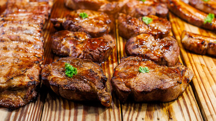 Close-up of multiple grilled steaks arranged on a wooden board, each garnished with a small sprig of parsley. The steaks are beautifully seared with a glistening, juicy appearance, highlighting their 