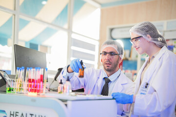 scientists perform experiments and record data. people arranges equipment with test tubes and chemicals for producing medicine and biochemistry. man hold tubes of chemical liquids and plant samples.