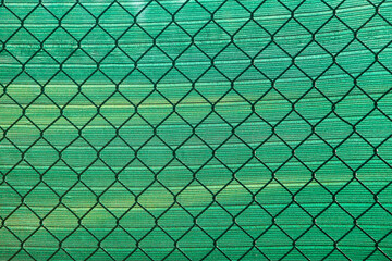 Chain link fence with green mesh background texture, sports field