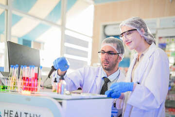 scientists perform experiments and record data. people arranges equipment with test tubes and chemicals for producing medicine and biochemistry. man hold tubes of chemical liquids and plant samples.