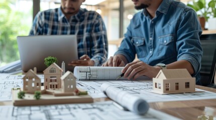 engineer and an architect sitting at a conference table with blueprints, laptops, and architectural models, engaged in a detailed planning session