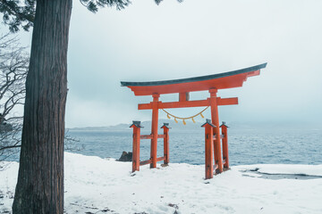 Red Japanese Torii gate of Goza no Ishi Shrine at lake tazawa in winter, located in Semboku city, Akita Prefecture, northern Japan. Landmark and famous for tourists attractions in Tohoku region, Japan
