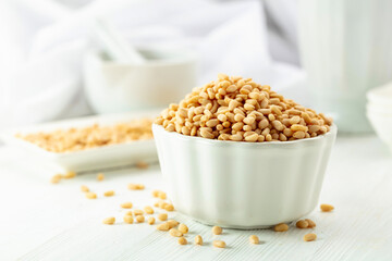 Pine nuts in white dish on a white background.