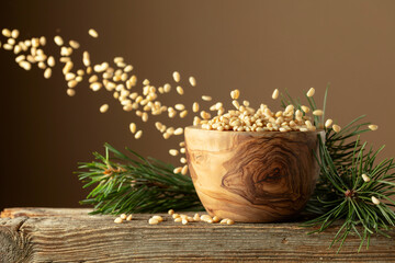 Flying peeled pine nuts on a brown background.