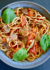 Spaghetti Primavera in a bowl garnished with baby spinach leaves. 