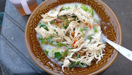 Bubur Ayam, a traditional Indonesian food consisting of white rice porridge, shredded chicken, cakwe, spring onions is usually served in the morning or evening.