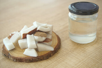 slice of fresh coconut and bottle of oil on a table 