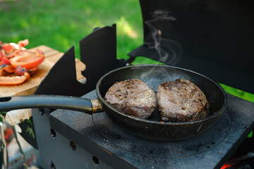 Two pieces of beef steak in a frying pan on grill