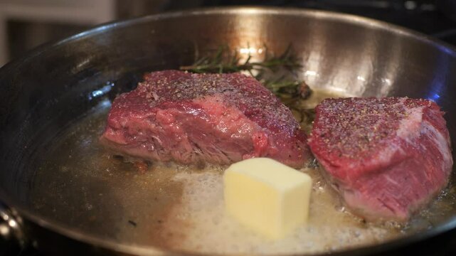 Filet mignon searing in butter with herbs 