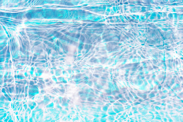 Blue water with ripples on the surface. Defocus blurred transparent blue colored clear calm water surface texture with splashes and bubbles. Water waves with shining pattern texture background.
