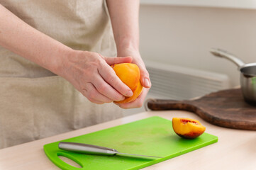 A female hand cuts a tasty juicy peach.
