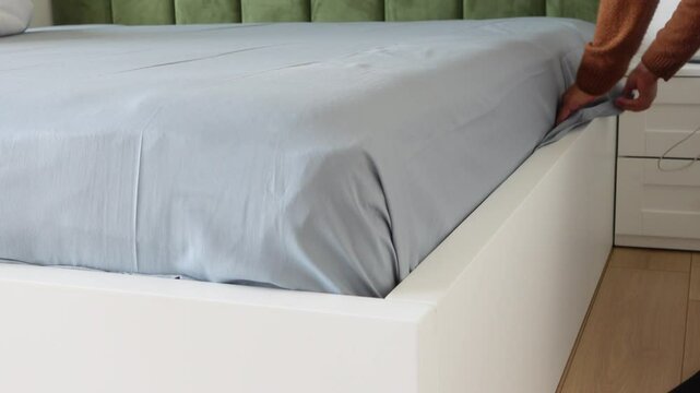 Arranging a bed sheet snugly over a mattress corner for a cozy and neat bedding setup