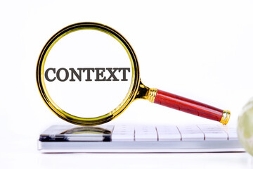 Conceptual context symbol. Copy space. Context word written through a magnifying glass standing on a calculator on a white background