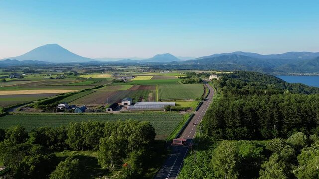 Toyako, Japan: Aerial drone footage of traffic on the countryside road along lake Toya and Mt Yotei volcano in the between Toyako and Niseko in Hokkaido in Japan in summer. 