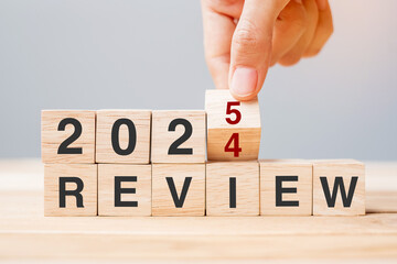 hand flipping block 2024 to 2025 REVIEW text on table. Resolution, idea, goal, motivation, reboot,...