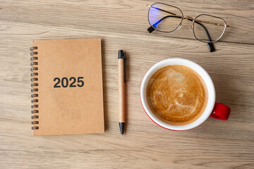 2025 notebook and coffee cup on wood table, Top view and copy space. Xmas, Happy New Year, Goals,...