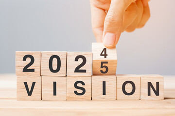 hand flipping block 2024 to 2025 VISION text on table. Resolution, strategy, goal, motivation, reboot, business and New Year holiday concepts