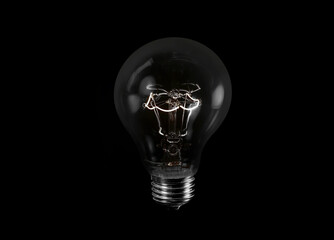 Black and white photo of tungsten light bulb isolated on black background 